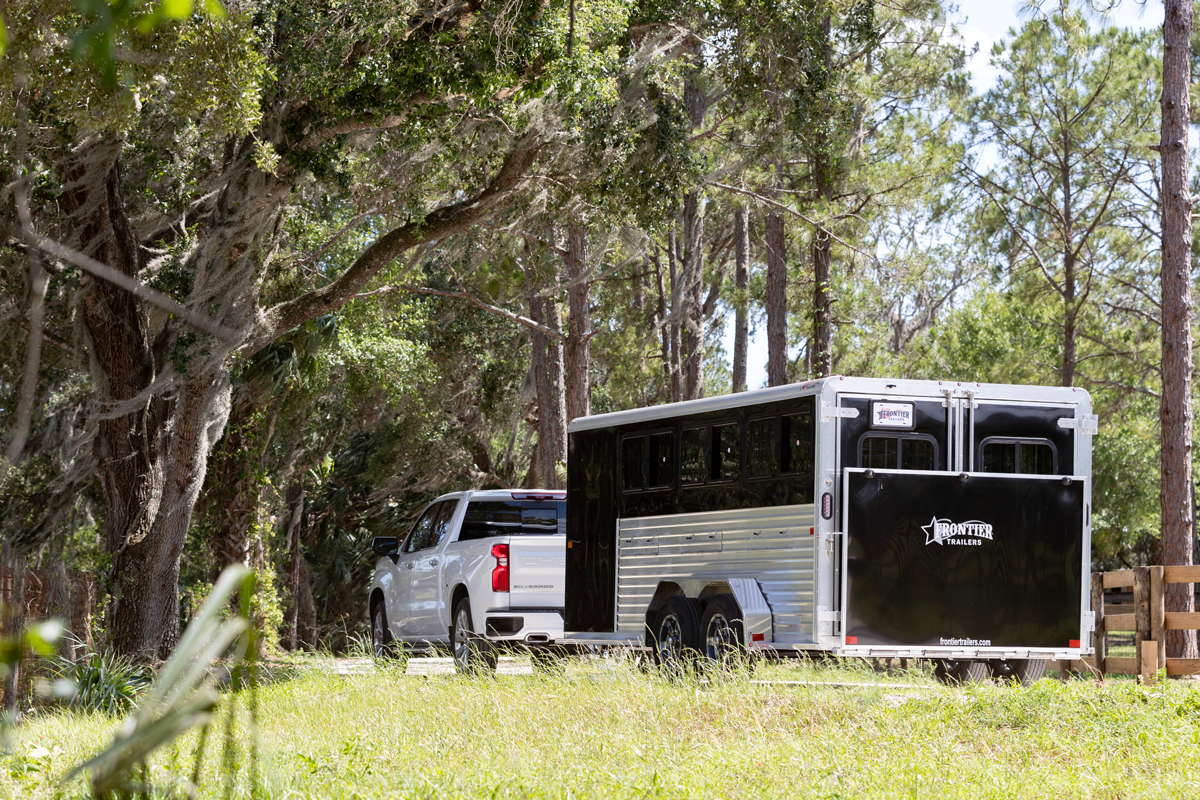 Black Stock LowPro DDFW Bumper Pull Series Being Pulled By White Truck Near Trees In Grassy Area