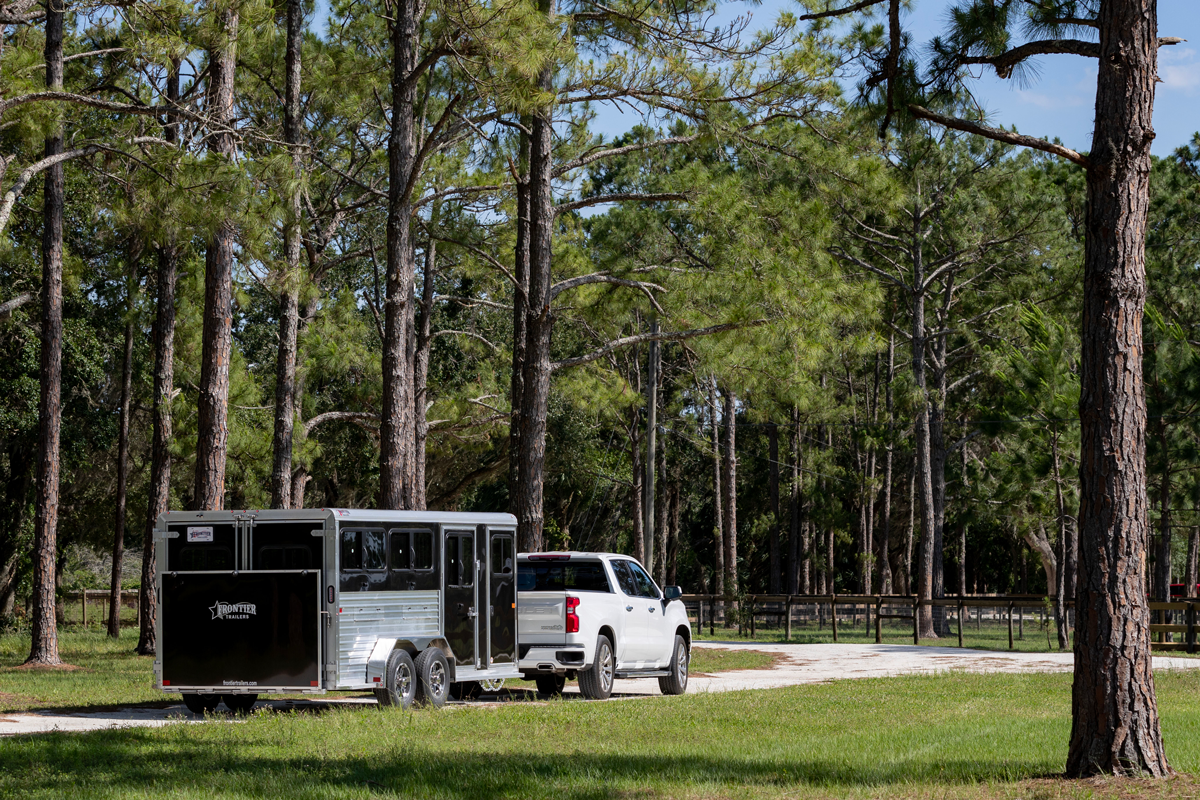 Black Stock LowPro DDFW Bumper Pull Series Being Pulled By White Truck Near Trees